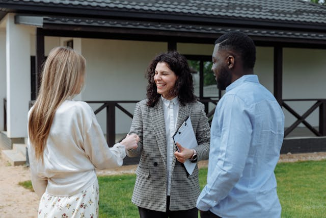 two people shaking hands with a property manager while standing outside a house