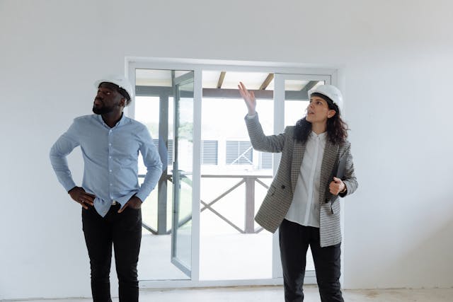 two people in hard hats looking at house two people in hard hats looking at house