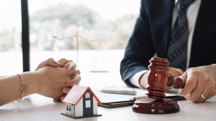 a contract, a gavel, and a home figurine